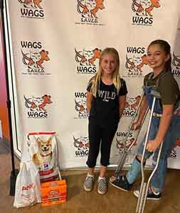 girls donate a dog and cat food at WAGS