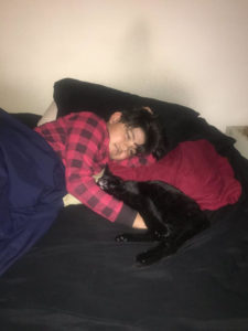 lucine resting on arms boy with red checkered jacket black bed